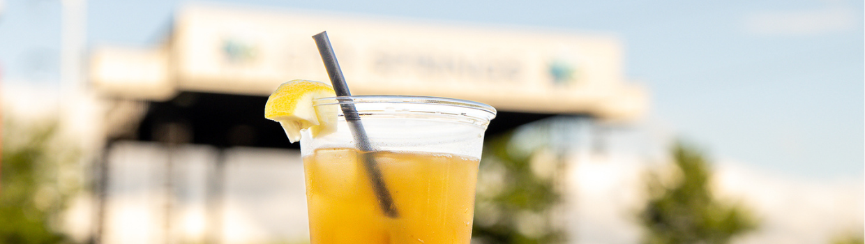 A beverage on ice, garnished with a lemon & straw, is displayed near the City Green stage.