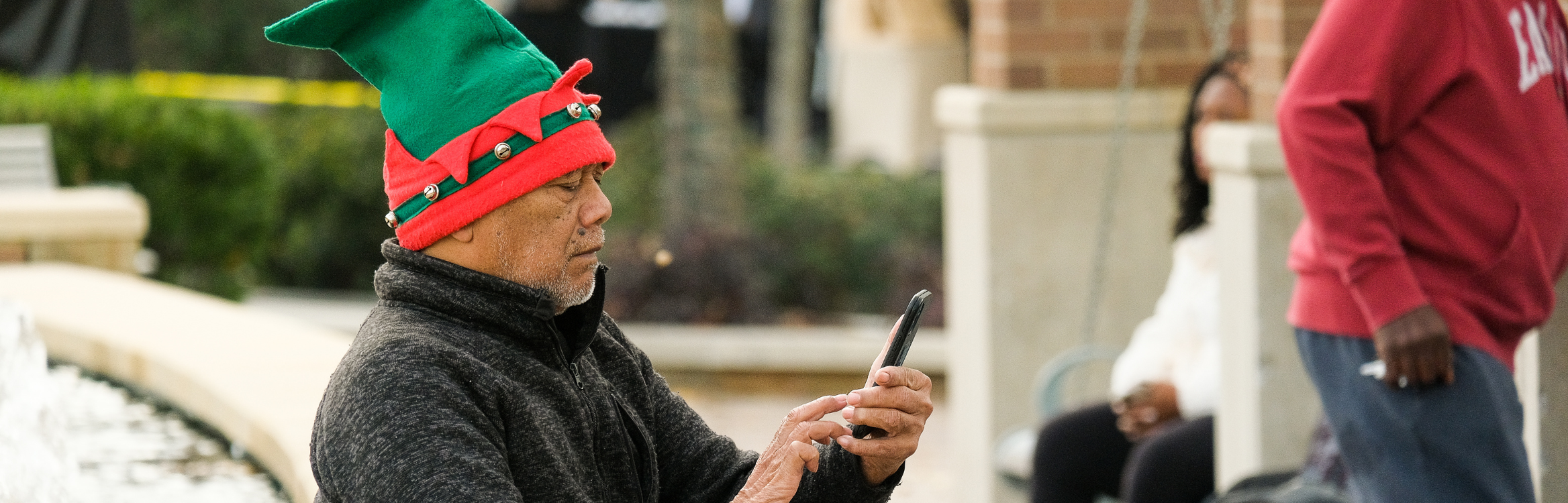 A man wearing an elf hat looking at his phone